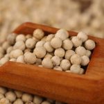 White peppercorns in a wooden scoop