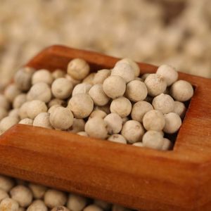 White peppercorns in a wooden scoop