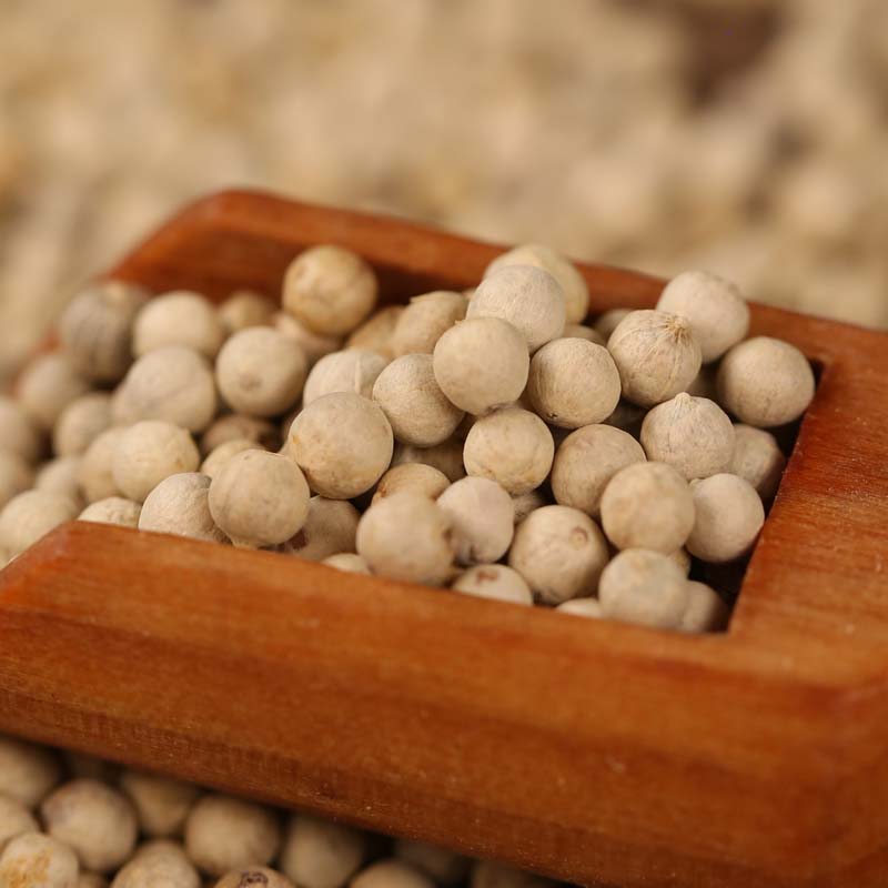 White peppercorns in a wooden scoop