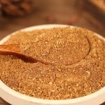 Red Sichuan pepper powder in a white bowl with a wooden spoon