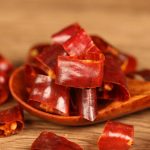 Huaxi dried chili segments on a wooden spoon