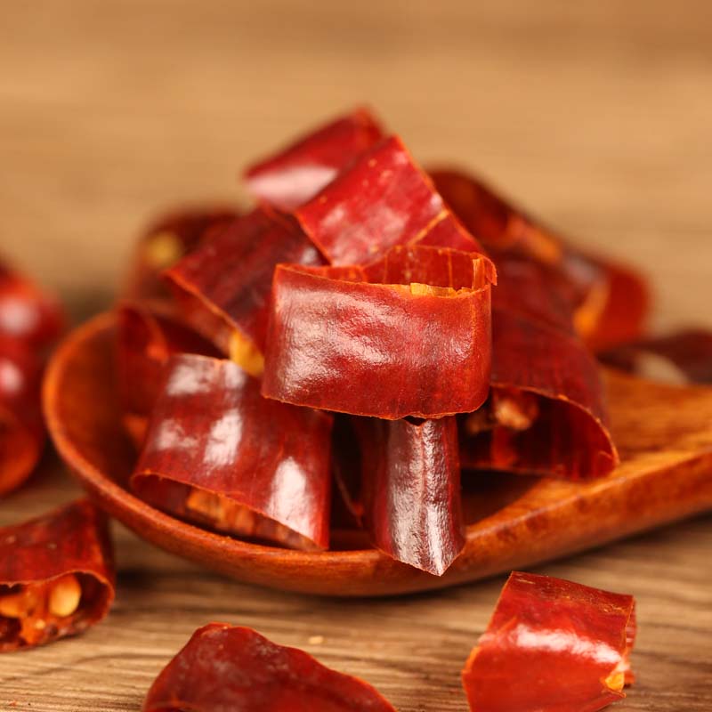 Huaxi dried chili segments on a wooden spoon