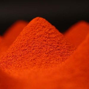 Super hot fine chili powder shaped into a smooth cone on a dark background