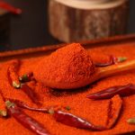 Huaxi fine-ground chili powder on a wooden spoon beside whole dried chilies