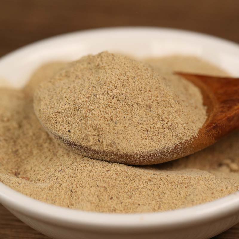 Ground white pepper in a white bowl with a wooden spoon