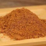 Ground cinnamon mounded on a wooden board