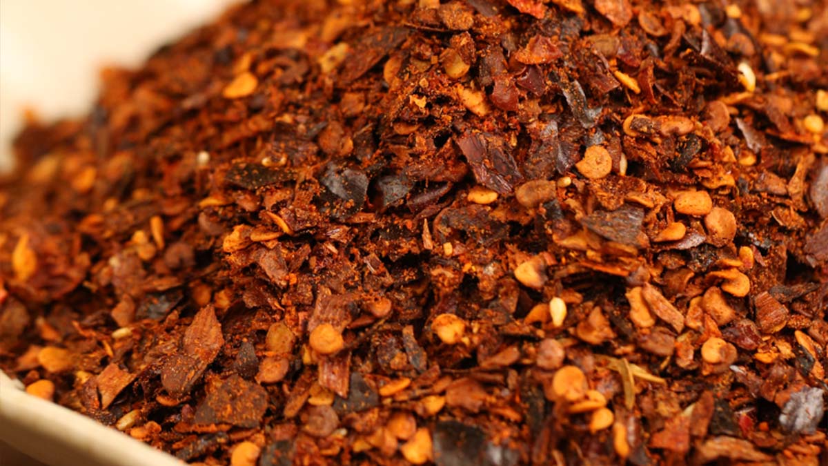 Dark red coarse chili flakes with seeds, close-up