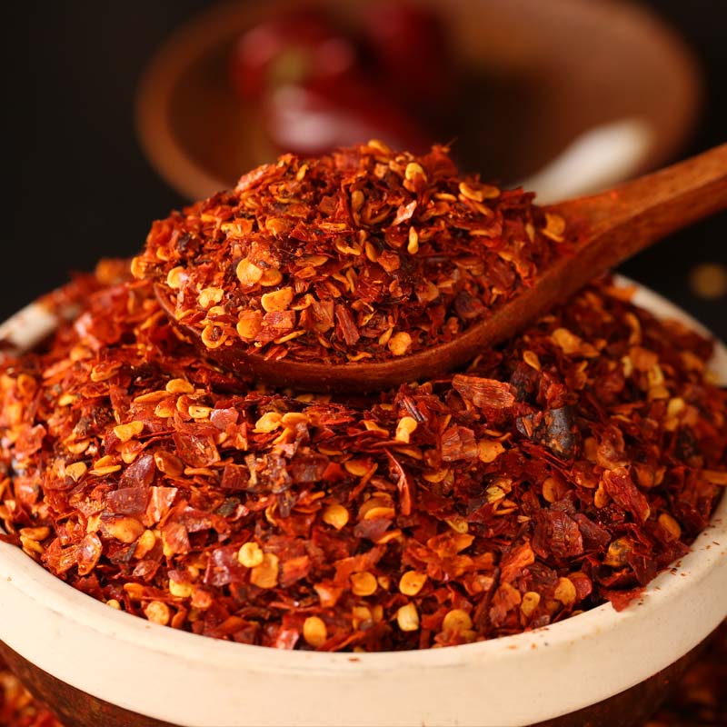 Chili powder for chili oil in a white bowl with a wooden spoon