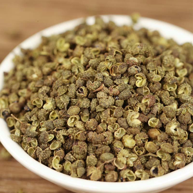 Green Sichuan peppercorns filling a white dish