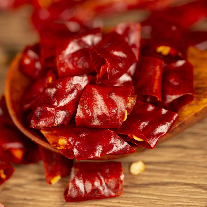 Xiaomila dried chili segments lifted on a wooden spoon